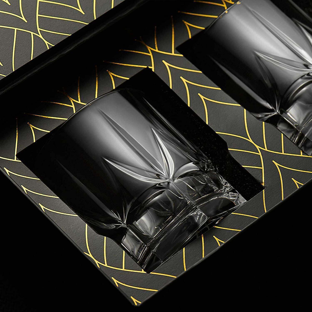 Two black crystal glasses on a decorative black tray with gold leaf patterns